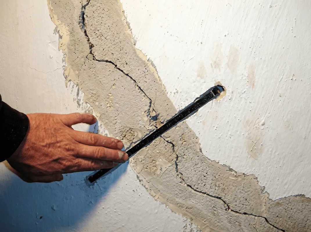 A wall with a large crack is being inspected by a professional in Aurora, IL